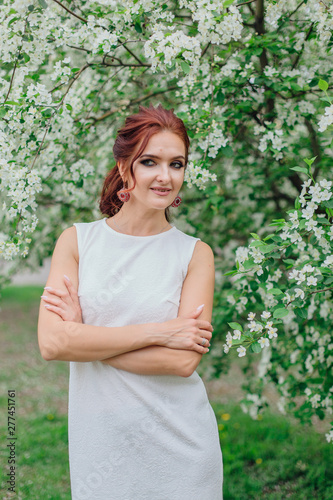 Charming woman wearing beautiful white dress under the apple tree