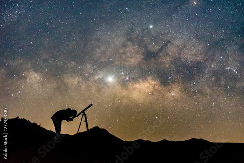 Silhouette of man watching star in telescope against  milky way galaxy with stars and space dust in the universe.