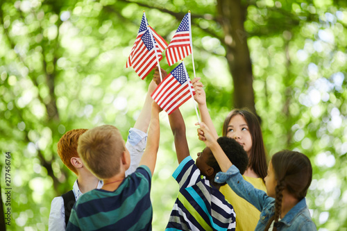Foto Group of patriotic multi-ethnic children standing in circle and raising us stick