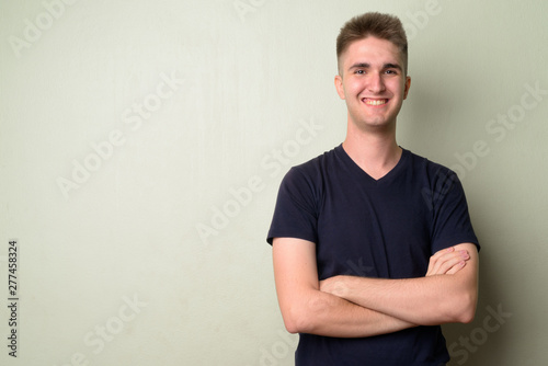 Portrait of happy young handsome man smiling with arms crossed