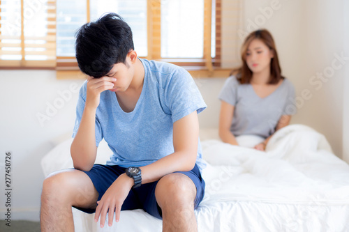 Asian young couple having problem of man worried impotent and unhappy at bedroom, trouble divorce of family with frustrated, husband having depression, conflict of love concept. photo