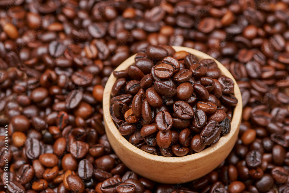 Fototapeta premium Wooden bowl with roasted coffee beans on rustic background.