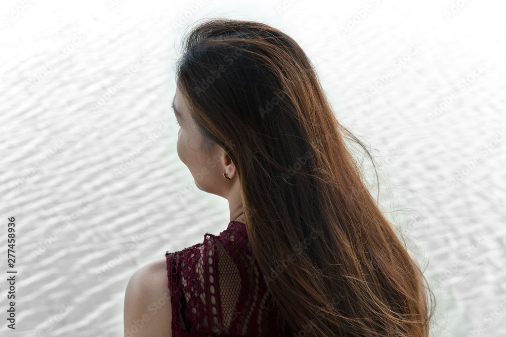 30-40s adult portrait behind of woman long hair with white wave water lake background 30-40s adult portrait behind of woman long hair with white wave water lake background