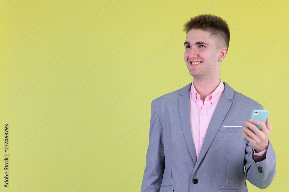 Happy young handsome businessman thinking while using phone Happy young handsome businessman thinking while using phone