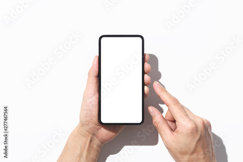 Closeup of hands touching black smartphone on white background with shadow. Blank screen.