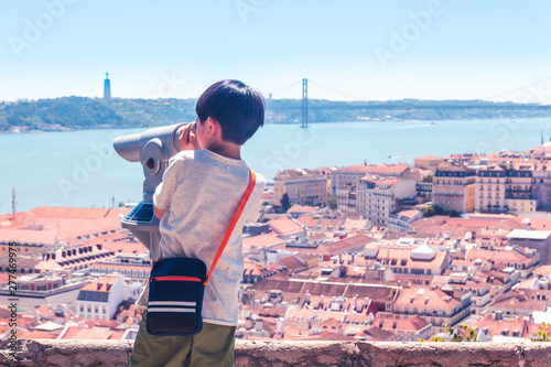 Little boy playing with a binoscope on the observation deck overlooking the old town photo