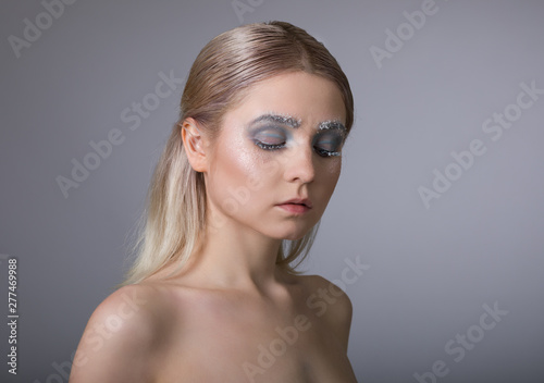 The face of a young woman with delicate face art in the winter style. Conceptual female makeup.