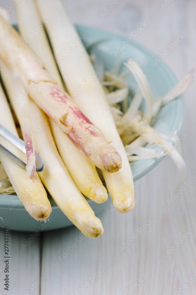 Bunch of raw uncooked white asparagus over rustic white wooden tray background. Seasonal harvest product. Local market food concept.  Top view, close-up