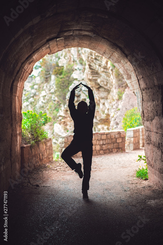 Woman practicing yoga in a dark tunnel