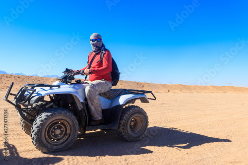 Young man in safari trip through egyptian desert driving ATV. Quad bikes safari in the desert near Hurghada, Egypt