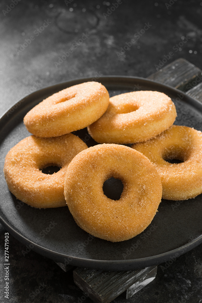 Donuts sprinkled with sugar. Dark background