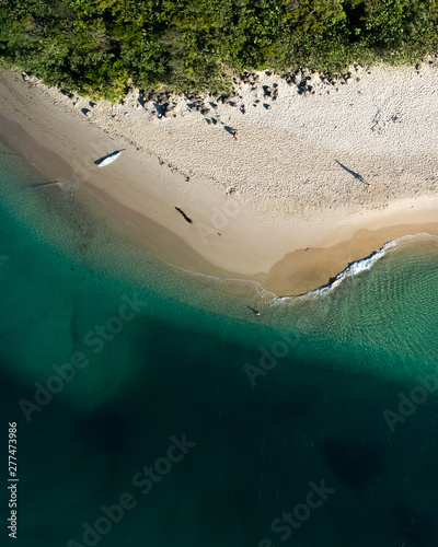 Aerial top view of beach with white sand, beautiful umbrellas and warm turquoise tropical water
