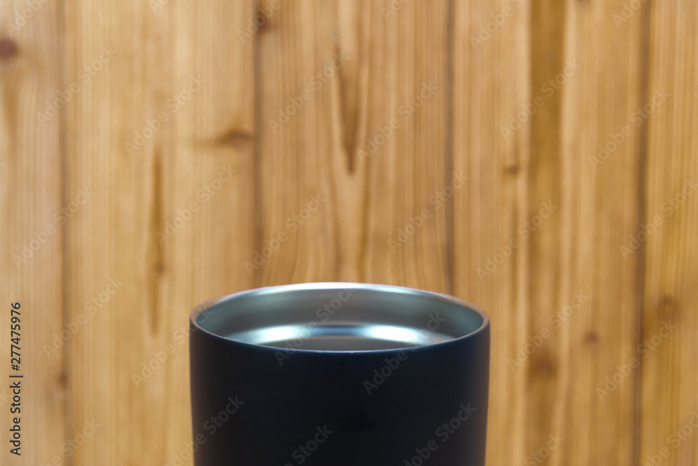Black colour stainless steel tumbler or cold and hot storage cup on wood. Black colour stainless steel tumbler or cold and hot storage cup on wood.