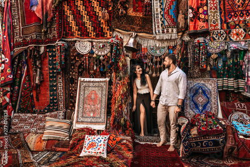 Man and woman in the store. Couple in love in Turkey. Man and woman in the Eastern country. Happy couple travels the world. Persian shop. Tourists in store. Oriental carpet. Istanbul. Follow me
