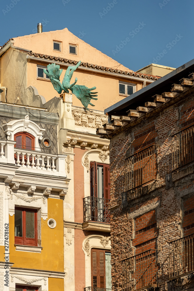 Obraz premium Madrid, Spain. Air accident. The sculpture of angel on the roof of the house, the sculptor Miguel Angel Ruiz. Bronze figure adorns the fasade of a building on Calle Milaneses, near to the Plaza Mayor.