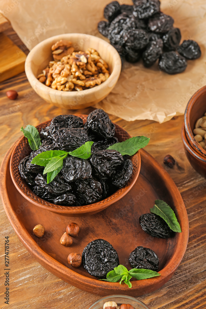 Bowl and plate with tasty prunes on wooden table Bowl and plate with tasty prunes on wooden table