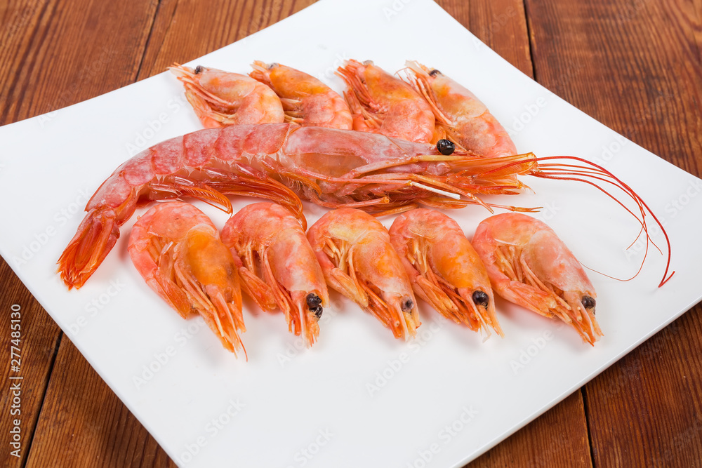 One king prawn among usual shrimps on square dish closeup One king prawn among usual shrimps on square dish closeup