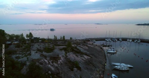 Aerial, tracking, drone shot, of a ferry, outside sirpalesaari island, at Merisatama harbor, on the Gulf of Finland, at dusk, on a dark and moody, summer evening. in Helsinki, Uusimaa, Suomi photo