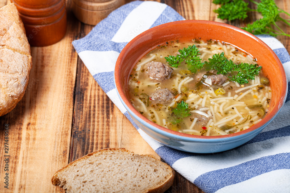 Homemade soup with noodles and meatballs on a wooden table. Traditional rural dinner Homemade soup with noodles and meatballs on a wooden table. Traditional rural dinner