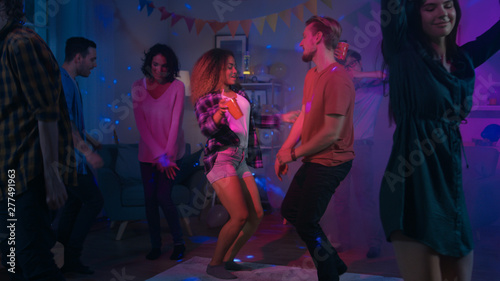 At the College House Party: Diverse Group of Friends Have Fun, Dancing and Socializing. Boys and Girls Dance in the Living Room. Disco Neon Strobe Lights Illuminating Room. 