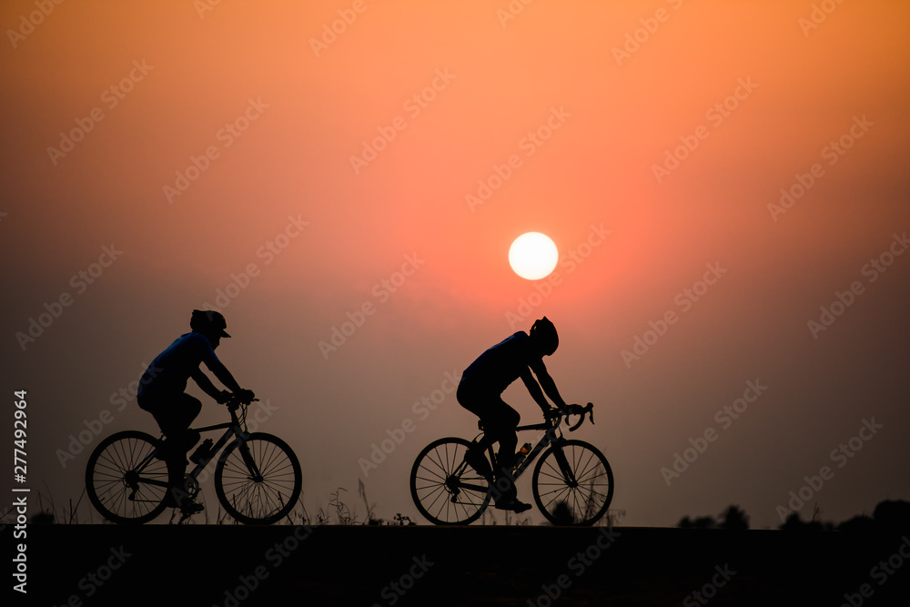 Silhouette man cycling on sunset background