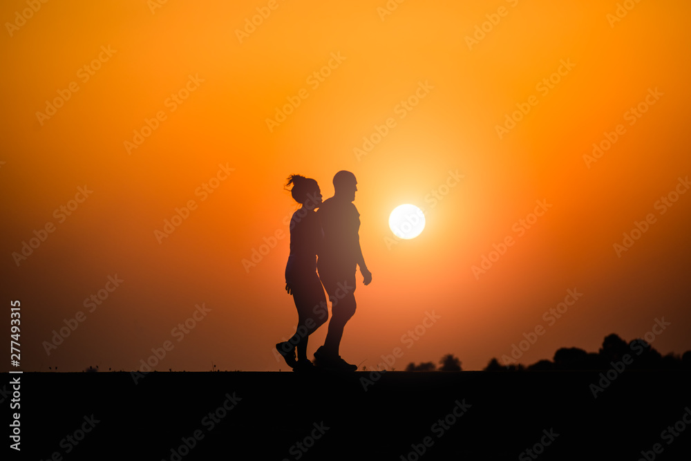 man and woman walking on sunset background man and woman walking on sunset background