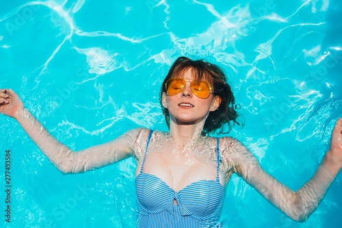 Redhead woman in blue swimming pool.