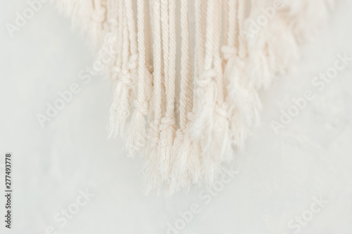 Close up of cotton macrame panel fringe in a minimalistic scandinavian wall. Texture. Background.