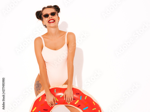 Young beautiful sexy smiling hipster woman with red lips in sunglasses.Girl in summer swimwear bathing suit with donut lilo inflatable mattress.Positive female going crazy.Funny model isolated