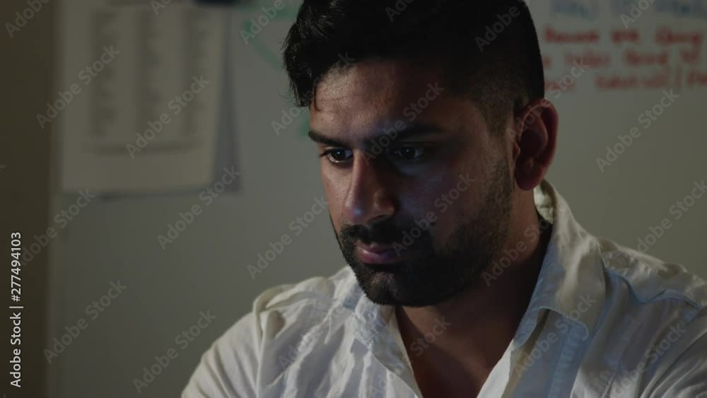 Man Works Back Late in Dark Office at Night, Checks Notes and Types on Computer