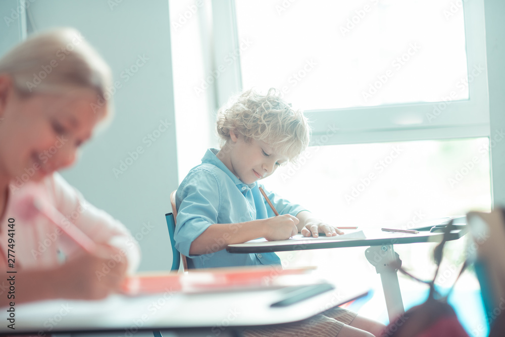 Blond-haired boy sitting near the window in class. Blond-haired boy sitting near the window in class.