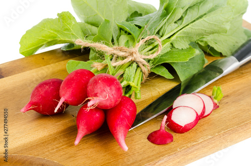 Bunch of fresh red radish on wooden cutting board for cooking.