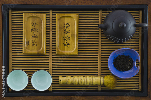 An arrangement of a tea pot; cups; brush; herbs on wooden tray photo