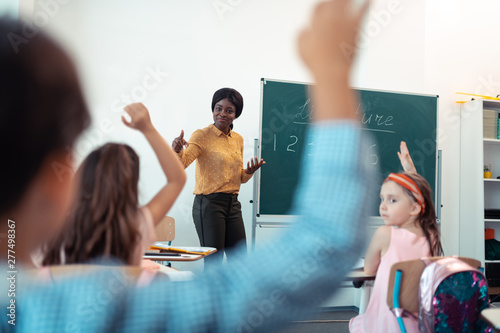 Dark-skinned teacher feeling satisfied with work of pupils photo