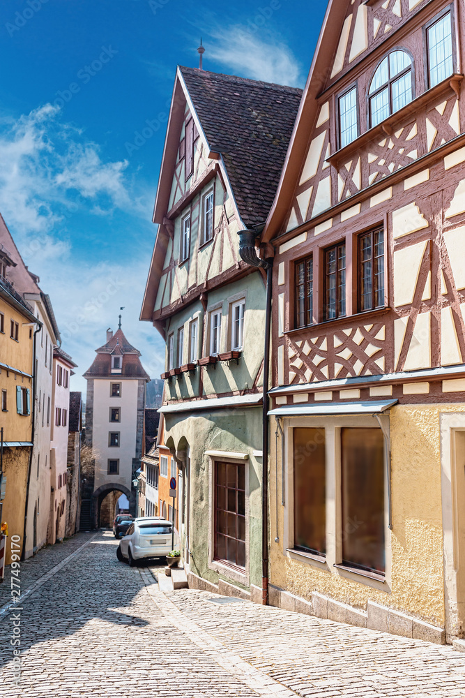 view of a narrow stone-paved street with beautiful half-timbered houses in the old German town of Dinkelsbühl