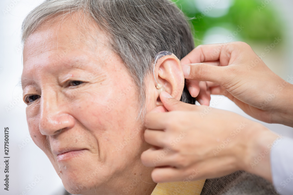 Obraz premium Doctor help patient wear audiphone