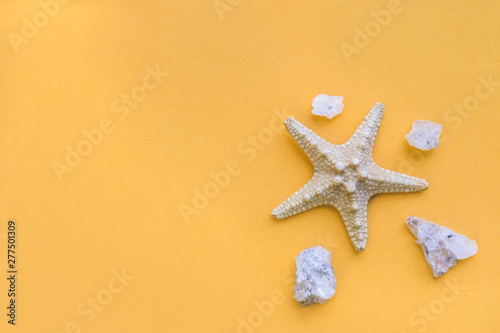 Starfish and small sea stones on an yellow background. Sea summer theme