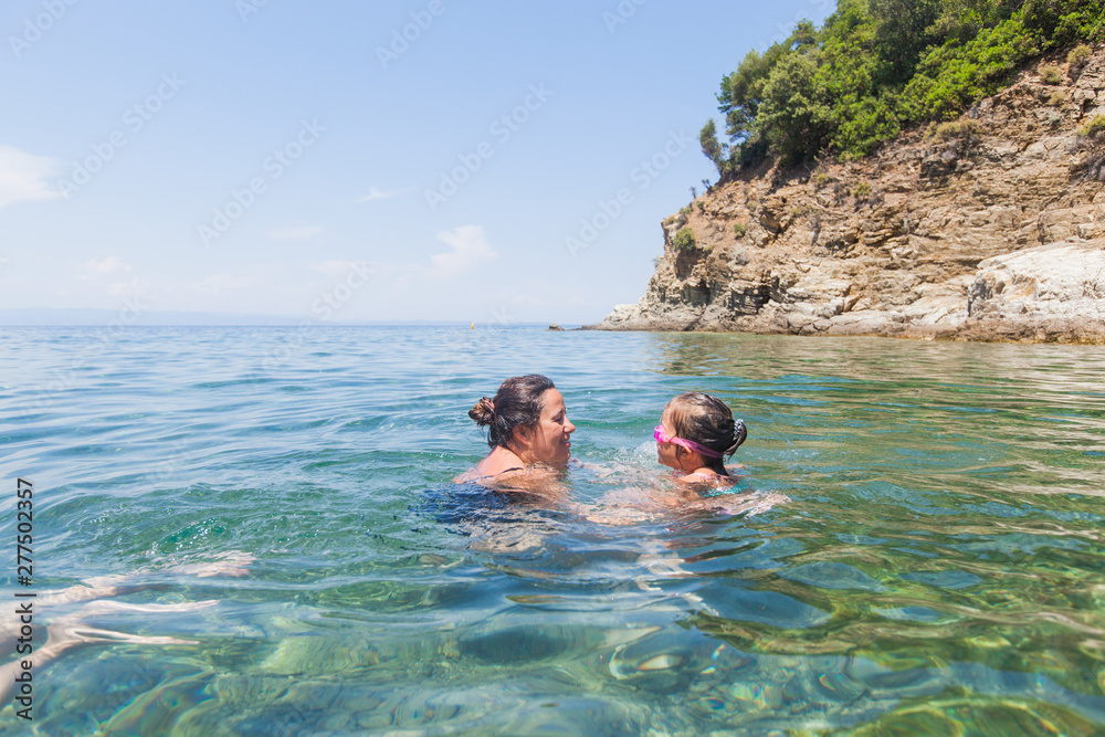 Mother and daughter having fun together in the sea during vacation