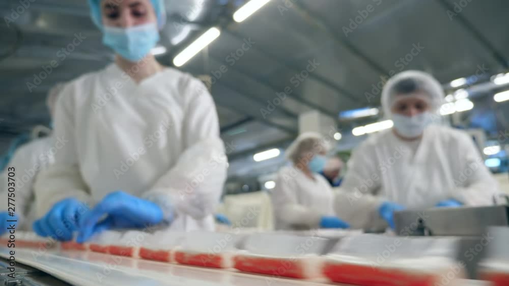 Women take food from a factory conveyor, packing.