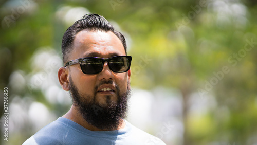 Middle aged, asian long bearded man in sunglasses under the sunlight, outdoor.