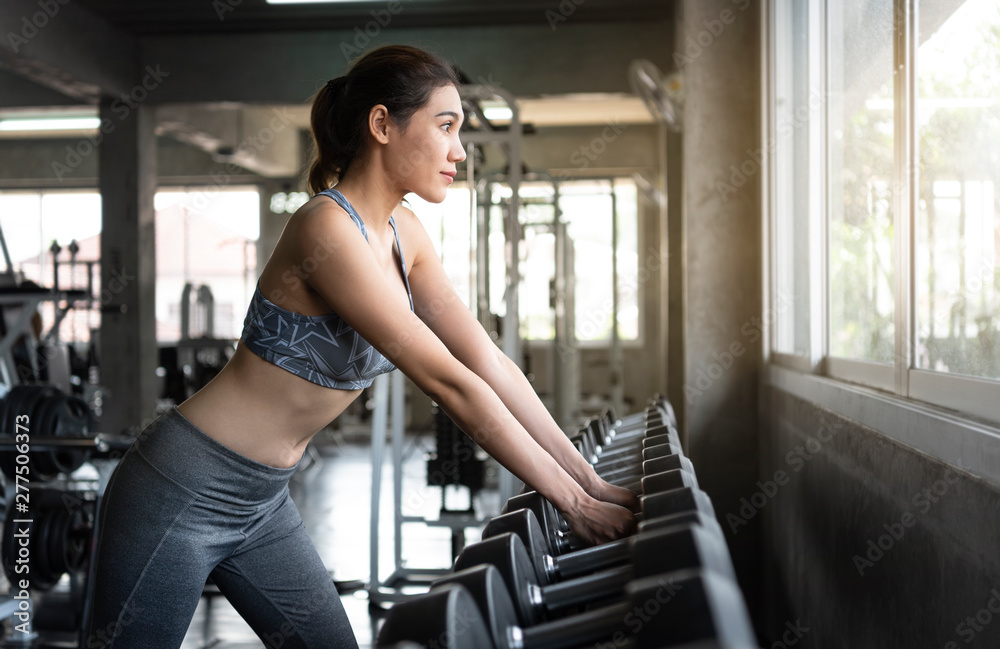 Young asian woman lifting dumbbells in gym. healthy lifestyle and workout motivation concept. Young asian woman lifting dumbbells in gym. healthy lifestyle and workout motivation concept.