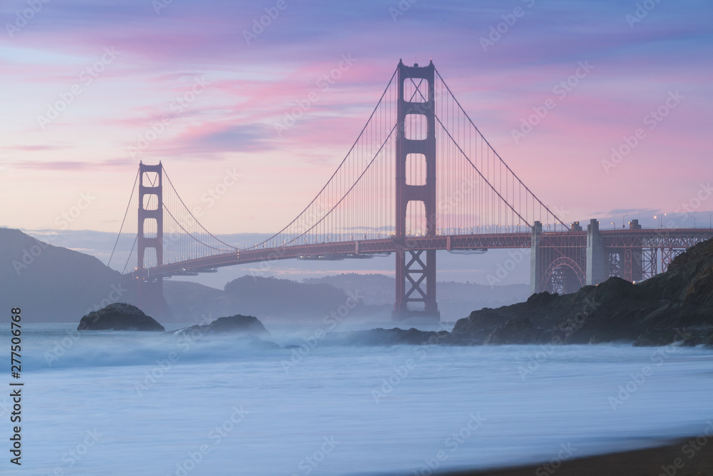 Obraz premium Classic panoramic view of famous Golden Gate Bridge seen from scenic Baker Beach in beautiful golden evening light on sunset with blue sky and clouds in summer, San Francisco, California, USA