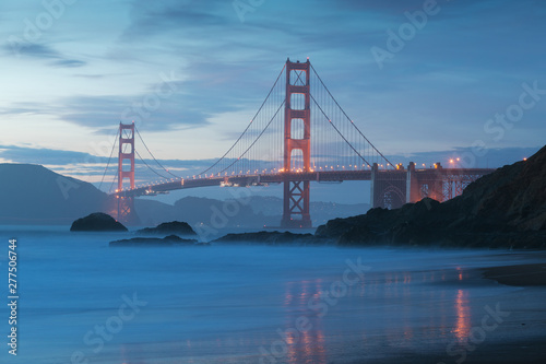 Classic panoramic view of famous Golden Gate Bridge seen from scenic Baker Beach in beautiful golden evening light on adusk with blue sky and clouds in summer  San Francisco  California  USA