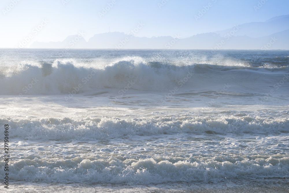Amazing sunny day with endless horizon and incredible foamy waves. Beautiful beach, California, USA seascape and sun on blue sky background Amazing sunny day with endless horizon and incredible foamy waves. Beautiful beach, California, USA seascape and sun on blue sky background