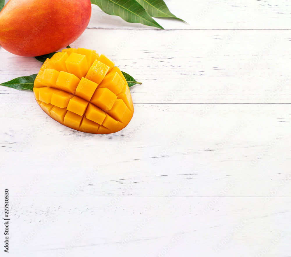 Beautiful chopped mango with green leaves on bright white color timber background. Above Top view, flat lay, copy space, close up. Tropical fruit concept. Beautiful chopped mango with green leaves on bright white color timber background. Above Top view, flat lay, copy space, close up. Tropical fruit concept.