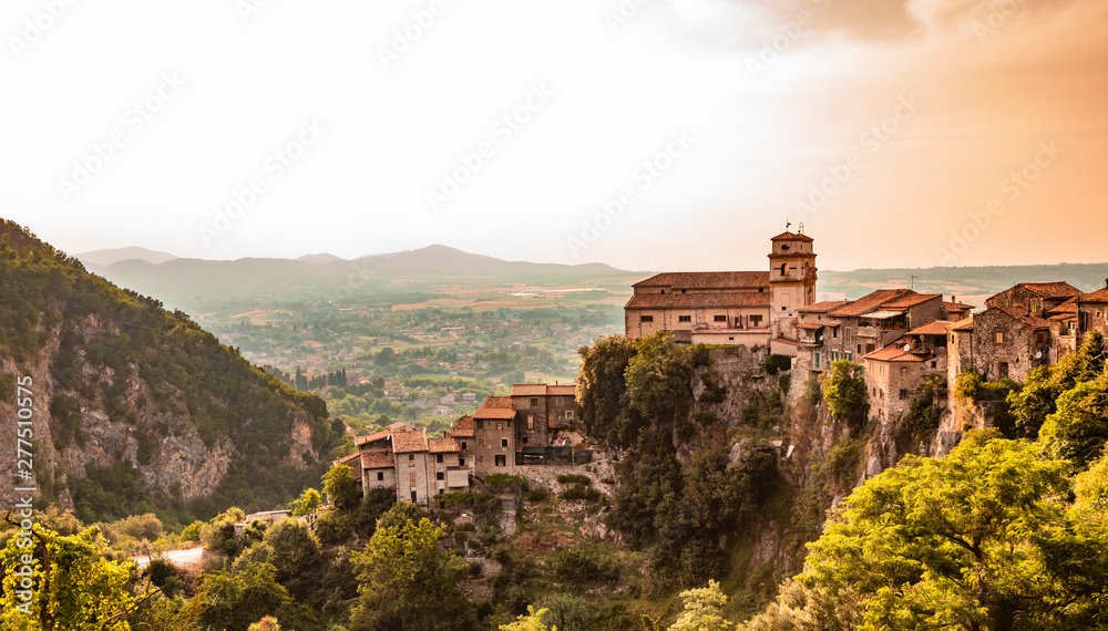 View of the valley of the Sacco River, from the ancient village of Artena. The town perched on the mountain. At the top of the cliff, the Church of Santa Croce. Trees and dense vegetation. At sunset.