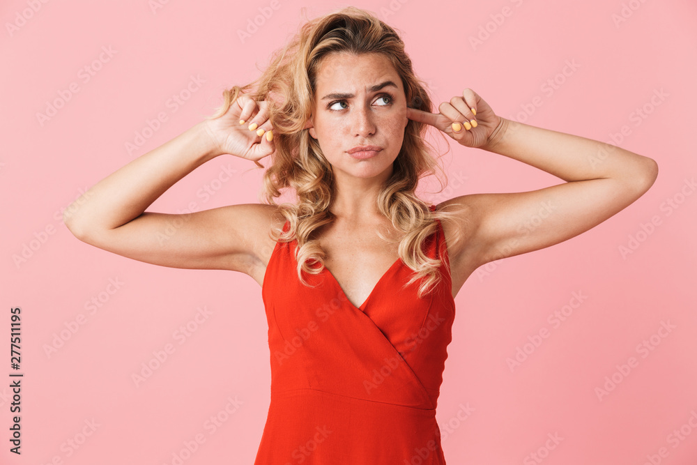 Displeased young pretty blonde cute woman in dress posing isolated over pink wall background covering ears because of loud. Displeased young pretty blonde cute woman in dress posing isolated over pink wall background covering ears because of loud.