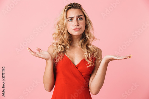 Confused displeased young pretty blonde cute woman in dress posing isolated over pink wall background.