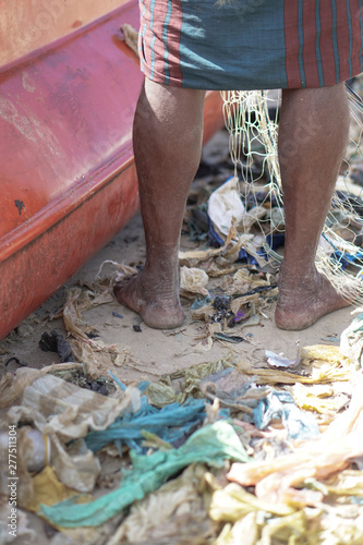 Bare feet in the garbage on the shores of the Indian Ocean. Ecological disaster with plastic and polyethylene. Stock photo