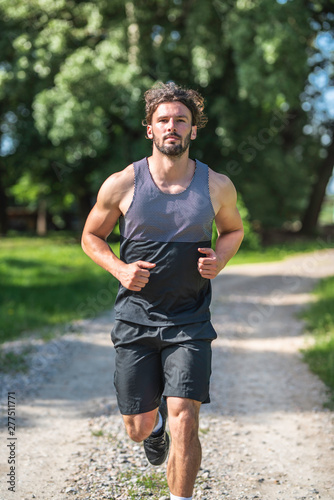 Young handsome man running on gravel road in nature vertical